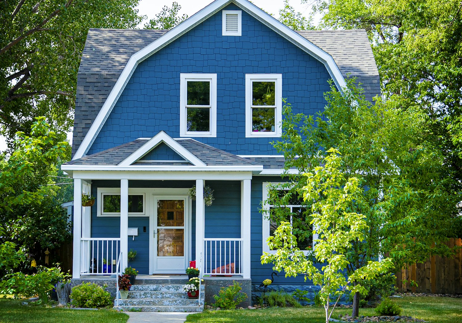 A blue two-story home with fresh white-trimmed windows and a covered front porch